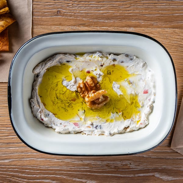 Zazzy's Lebanese labneh dip, drizzled with olive oil and garnished with walnuts, served in a white dish.